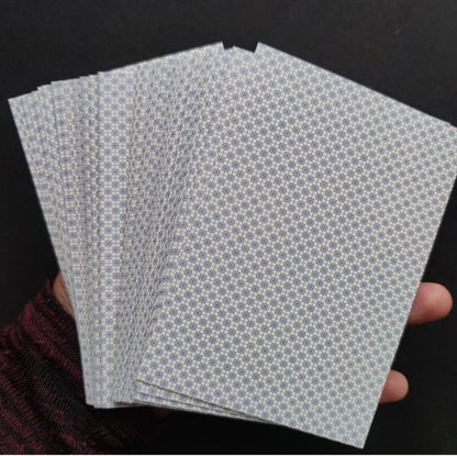 Dos des cartes du Grand Jeu de Mademoiselle Le Normand étalées dans une main, avec les tranches visibles.